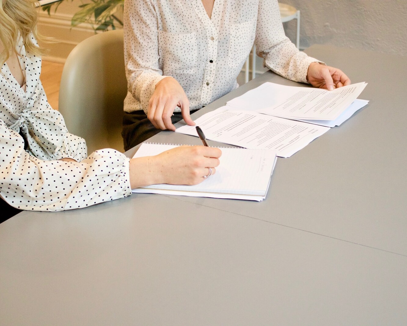 Ecole Anniviers woman signing on white printer paper beside woman about to touch the documents